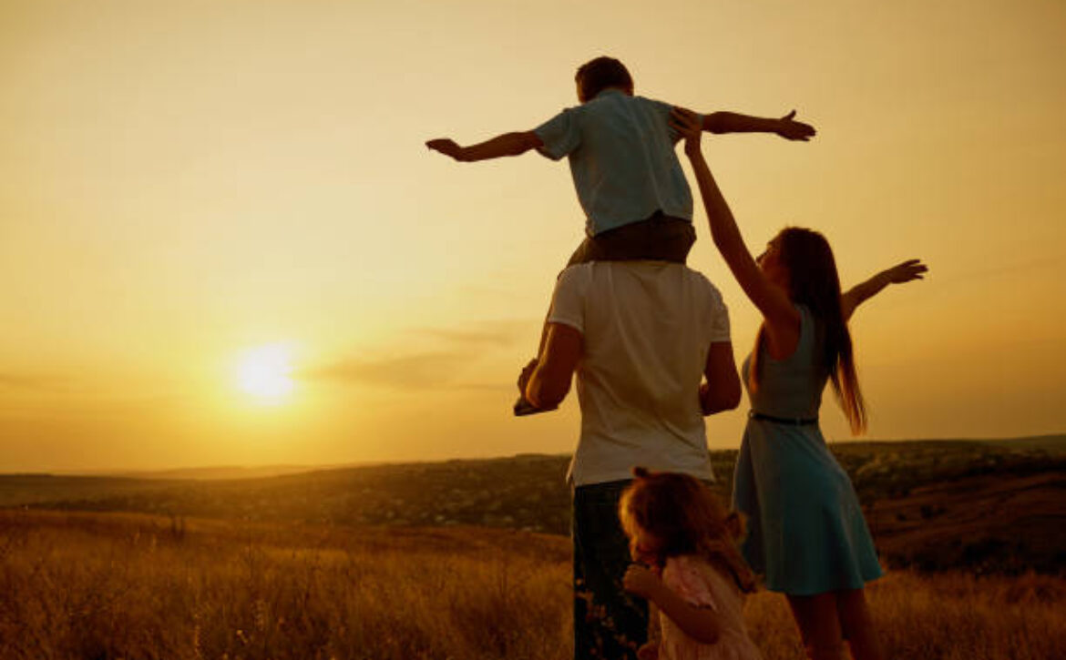 Happy family in the field at sunset in the summer autumn.